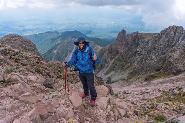 Een schilderachtig uitzicht van een Spaanse man die wandelkleding draagt en poseert op een bewolkte hemelachtergrond