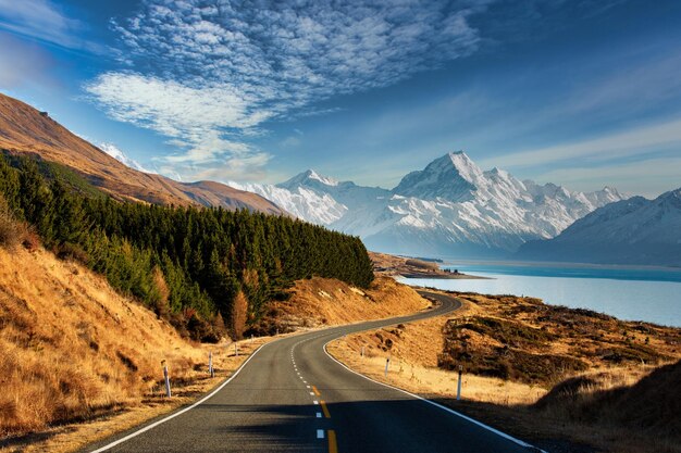 Foto een schilderachtige weg die langs de oever van het alpine meer pukaki slingert met de berg cook op de achtergrond