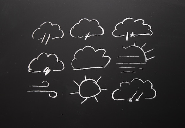 Foto een schoolbord met krijttekeningen van wolken en zon meteorologie icoon
