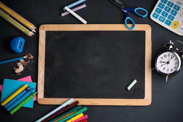 Een schoolbord op hout achtergrond met schoolbenodigdheden bovenaanzicht