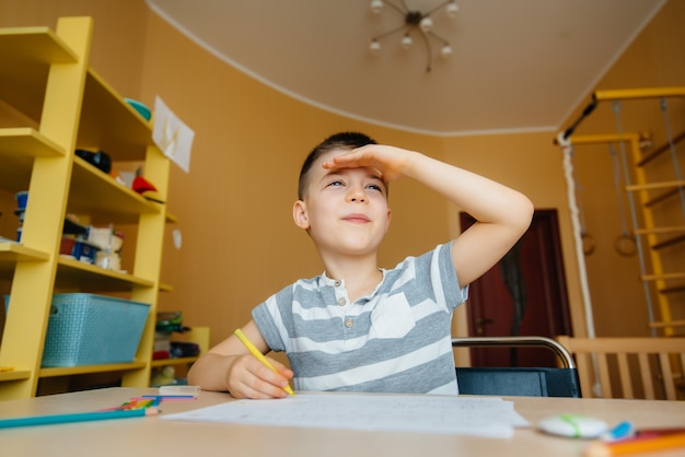 Een schoolgaande jongen maakt thuis huiswerk. Opleiding op school