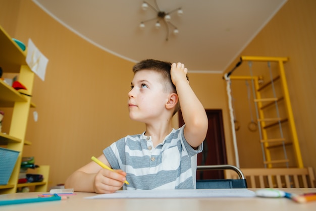 Een schoolgaande jongen maakt thuis huiswerk. Opleiding op school.