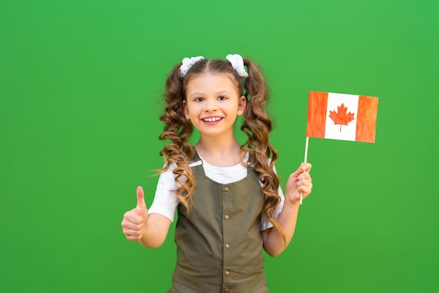 Een schoolmeisje houdt een Canadese vlag vast en lacht Studeren aan een Canadese school en een opleiding volgen