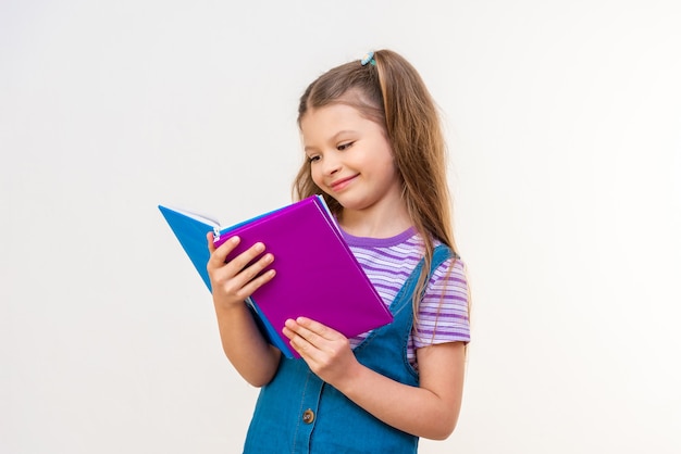 Een schoolmeisje leest een interessant verhaal in een boek op een witte achtergrond.