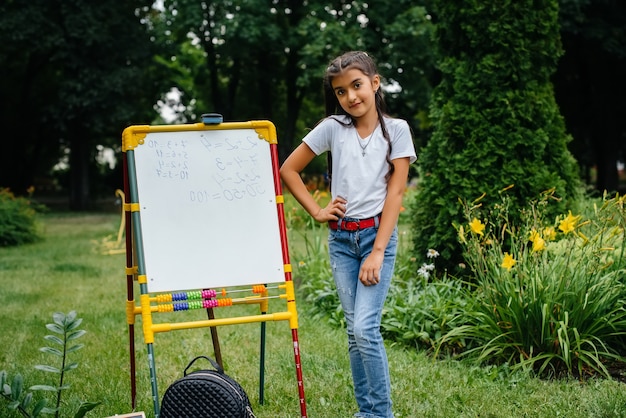 Foto een schoolmeisje schrijft lessen op een schoolbord en houdt zich bezig met buitentrainingen. terug naar school, leren tijdens de pandemie.