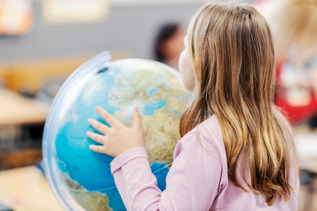 Een schoolmeisje zoekt naar de landen op de wereld tijdens de aardrijkskundeles