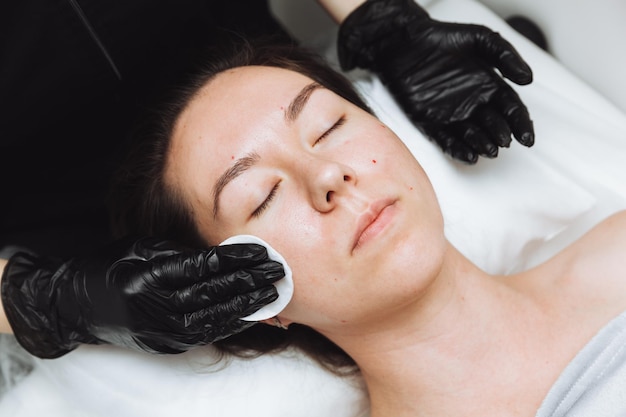 Een schoonheidsspecialist doet een cosmetische gezichtsmassage voor het gezicht van een ontspannen jonge vrouw in een beauty spa Gezichtsverzorging massage huidverzorging cosmetologie concept