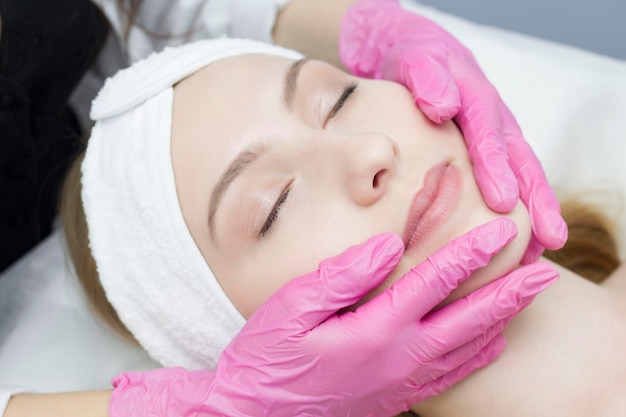 Een schoonheidsspecialiste doet verjongende gezichtsbehandelingen voor vrouwelijke klanten in een spa of salon Een schoonheidsspecialist geeft een patiënt een faceliftmassage in de kliniek van esthetische geneeskunde Schoonheidscosmetologie