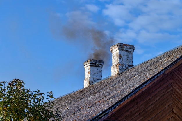 Een schoorsteen in een houten huis met zwarte rook