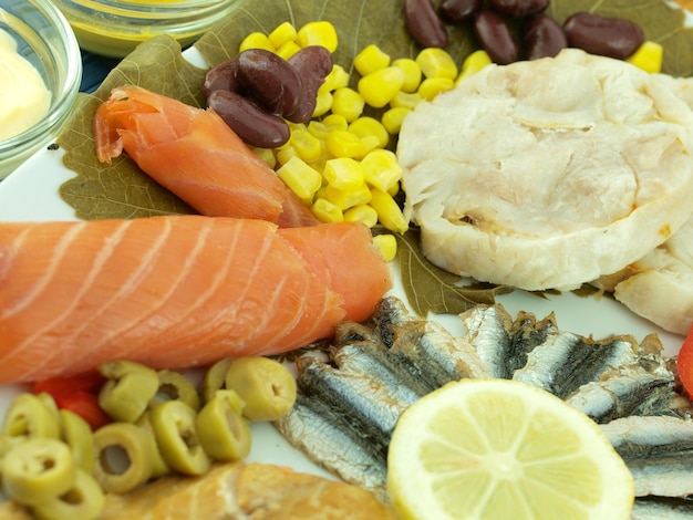 Een schotel met eten, waaronder vis, maïs en olijven