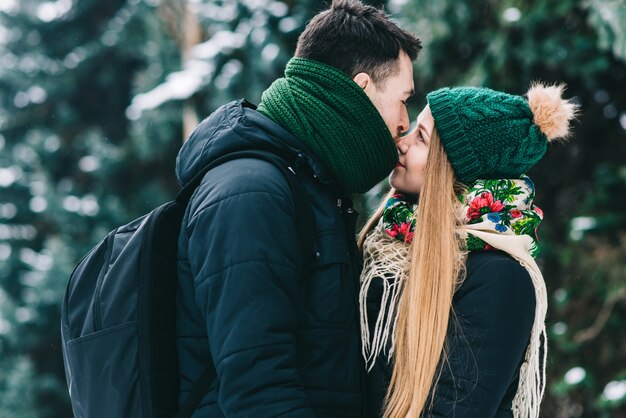 Een seconde voor de kus. Speels liefdevol stel heeft plezier in het winterpark. Ze knuffelen en lachen. Man bereidt zich voor om zijn vriendin te kussen