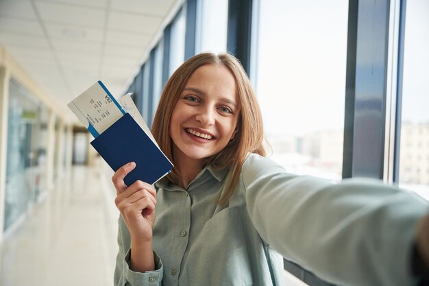 Foto een selfie maken met kaartjes in de hand. een jonge vrouw in de luchthavenhal.