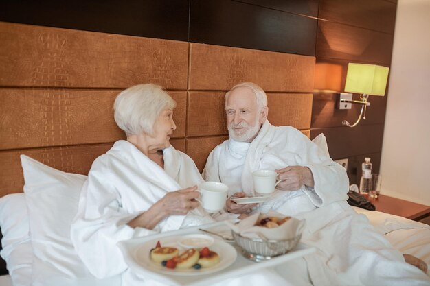 Een senior gelukkig stel dat geniet van het ontbijt terwijl ze in bed blijven