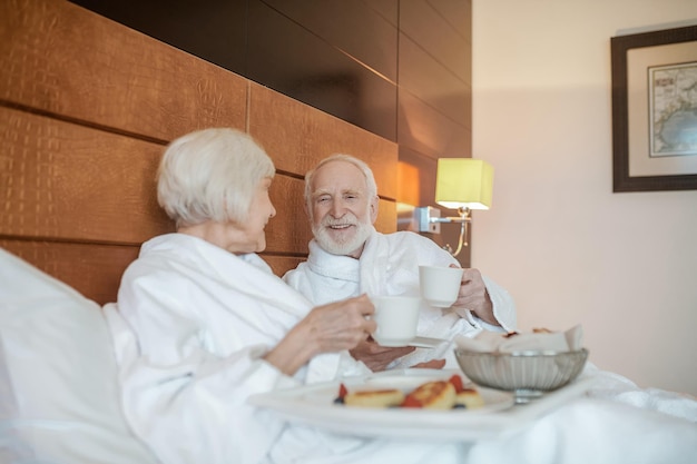 Een senior gelukkig stel dat geniet van het ontbijt terwijl ze in bed blijven