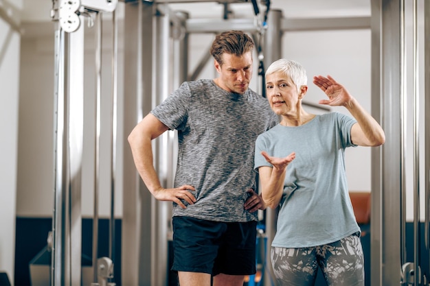 Een senior moeder en haar zoon van middelbare leeftijd praten voordat ze trainen in een sportschool.