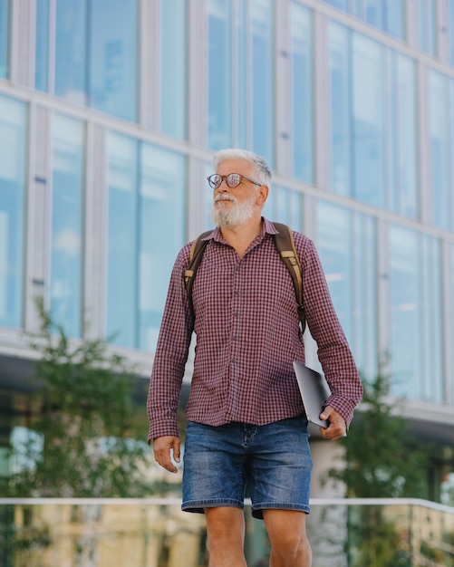 Een senior zakenman in een overhemd en met een laptop maakt carrière in een groot bedrijf