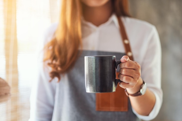 Een serveerster die een kop warme koffie vasthoudt en serveert in café