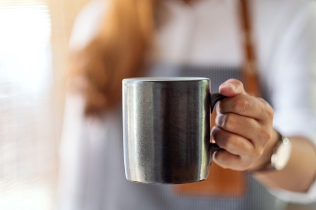 Een serveerster die een kop warme koffie vasthoudt en serveert in café