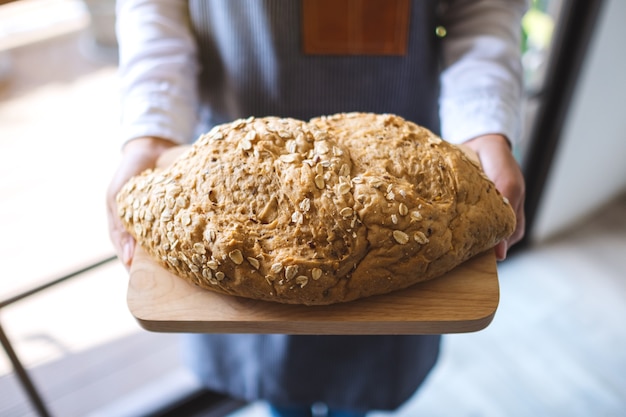 Een serveerster die een volkoren brood vasthoudt en serveert