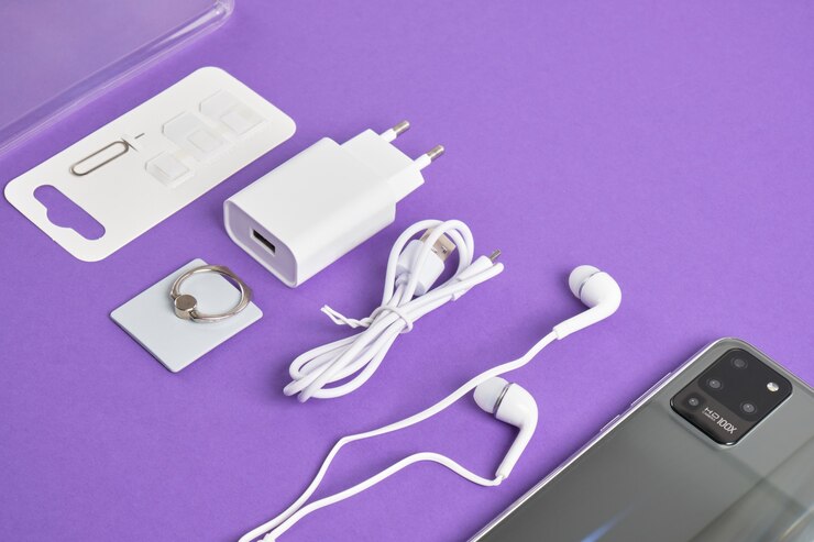 Een set accessoires voor een smartphone, telefoon, oplader, koptelefoon, een ringhouder, adapters voor simkaarten op een paarse achtergrond kopie ruimte bovenaanzicht