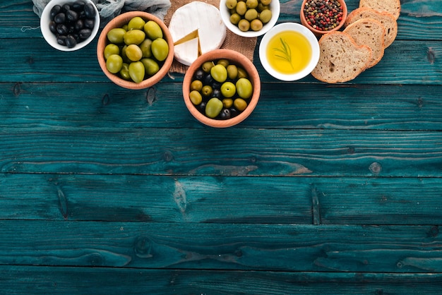 Een set groene olijven en zwarte olijven en snacks Op een blauwe houten tafel Vrije ruimte voor tekst