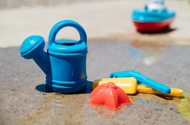 Een set kinderspeelgoed om in de zandbak te spelen Gekleurde hark schop gieter gemaakt van plastic close-up Vroege ontwikkeling van het kind het concept van vrijetijdsbesteding voor kinderen