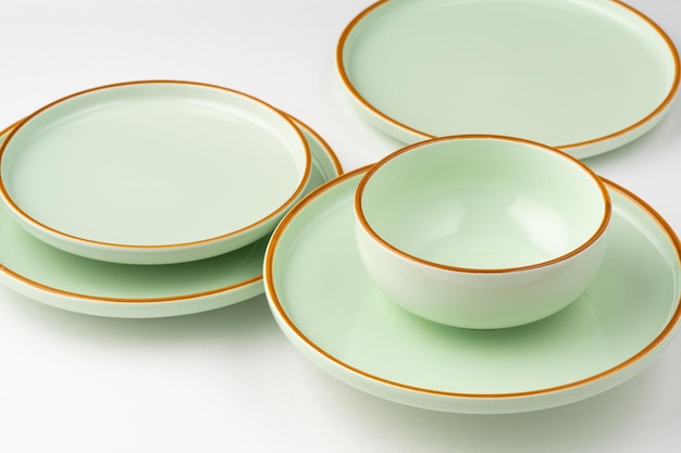 Een set pastelgroen servies van keramiek met oranje contouren