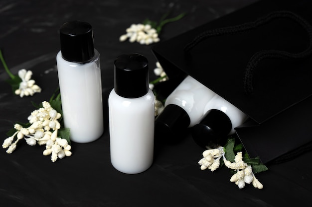 Een set potten met shampoo-cosmetica voor huid- en haarverzorging op een donkere achtergrond met witte bloemen.