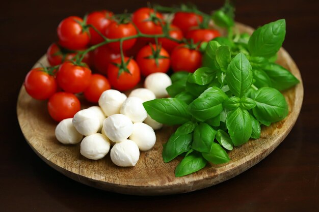 Een set producten voor caprese salade Tomaten basilicum en mozzarella op een houten plank