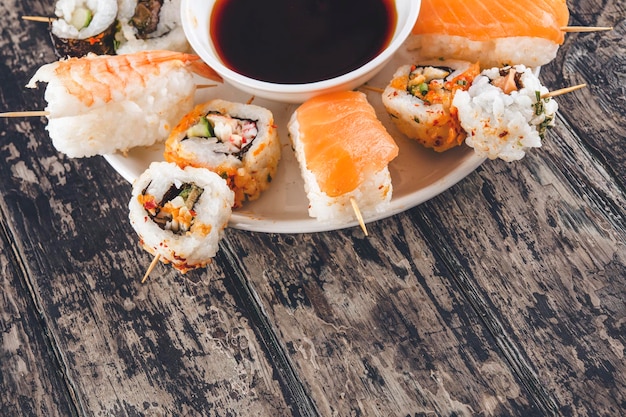 Een set sushi en sojasaus op een wit bord in de vorm van kant-en-klare canapés