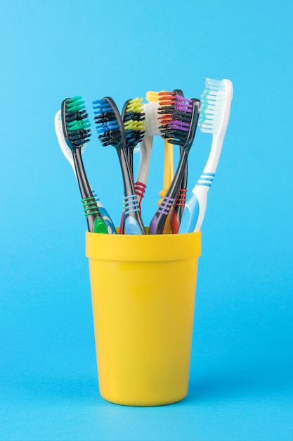 Een set tandenborstels in een gele plastic beker op een blauwe achtergrond
