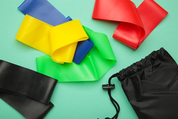 Een set van kleurrijke latex elastiekjes voor fitness en een zwarte hoes voor hen op mint achtergrond Sportconcept Ruimte voor tekst