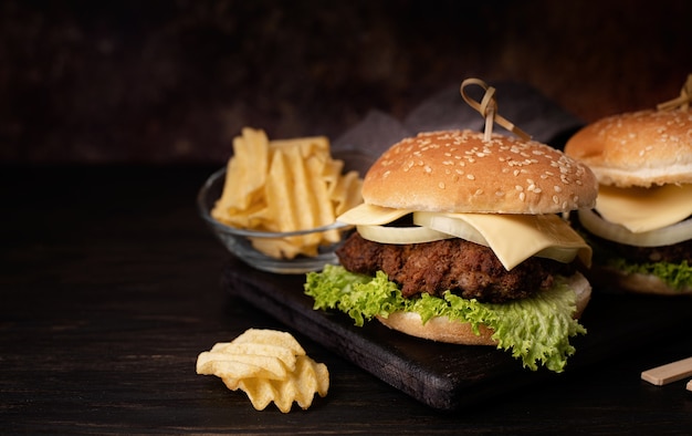 Een set zelfgemaakte heerlijke hamburgers van runderui, kaas en sla op een donkere houten achtergrond