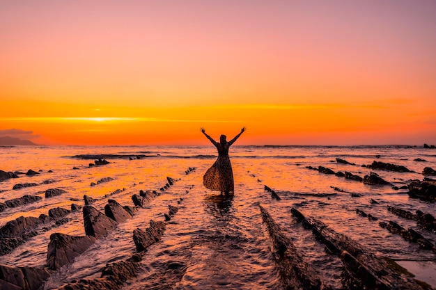 Een silhouet van een jong meisje in een jurk op het strand van Sakoneta in het dorp Deba