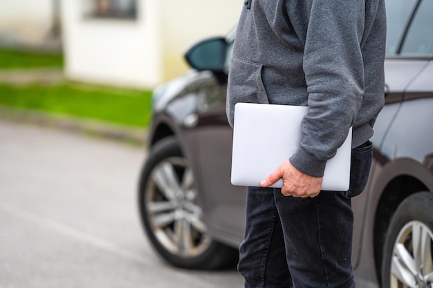 Een silhouet van een man met een computer in zijn handen op straat en een auto op de achtergrond