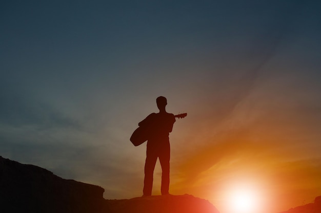 Een silhouet van een man met een gitaar hand in hand