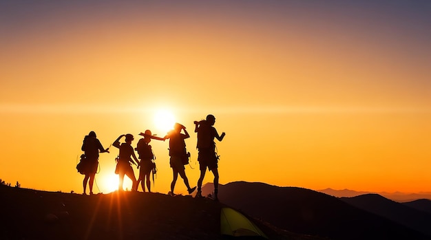 Een silhouet van groepsmensen heeft plezier op de top van de berg bij de tent tijdens de zonsondergang