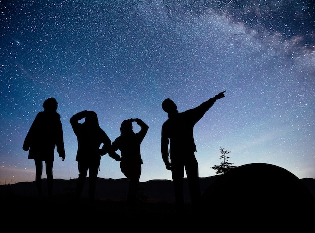 Een silhouet van groepsmensen vermaakt zich op de top van de berg bij de tent