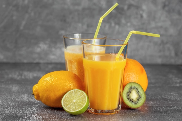 Een sinaasappel omwikkeld met een meetlint en een schuifmaat, omringd door vers fruit en glazen sap en smoothies. Het concept van afvallen, de figuur in vorm brengen.