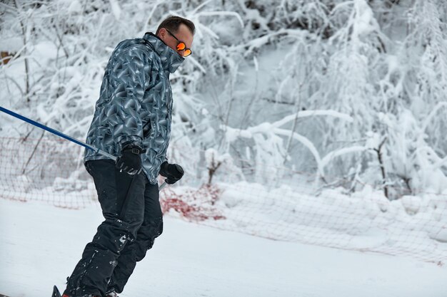 Een skiër in grijze jas rijdt de helling af op een ijzige dag.