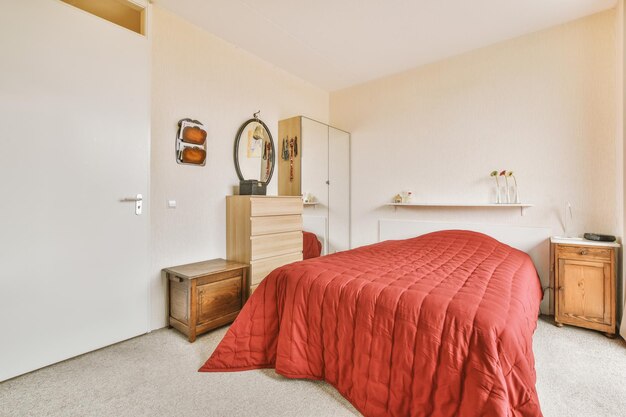 Een slaapkamer met een rood bed en een dressoir