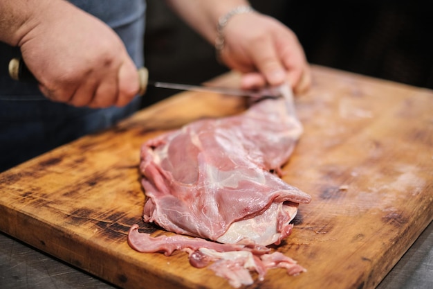 Een slager slacht een lamsbout om te grillen Pitmaster maakt vlees klaar om te roken