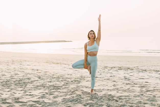 Een slank meisje beoefent yoga op het strand bij zonsondergang uitvoert asanas persoon