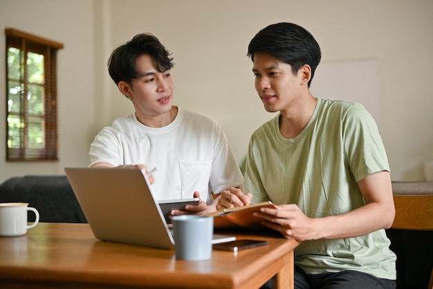 Een slimme jonge Aziatische mannelijke student geeft thuis bijles en helpt zijn vriend met wiskunde