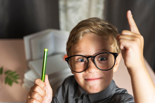 Een slimme jongen met een bril steekt enthousiast zijn vinger op naar nieuwe ontdekkingen