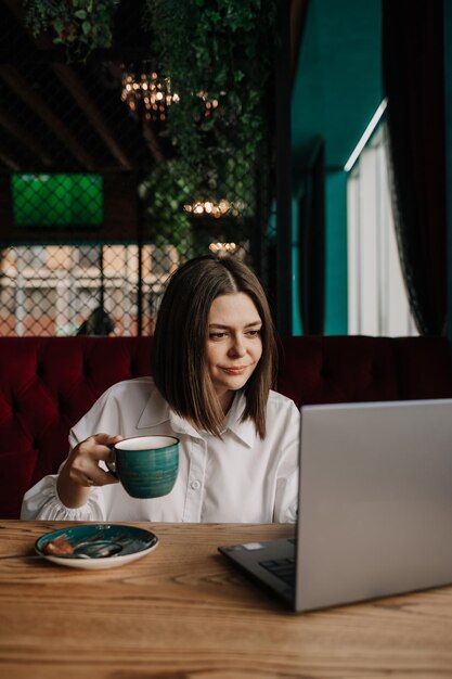 Een slimme zakenvrouw zit aan een tafel in een café met een kopje koffie op een laptop te werken