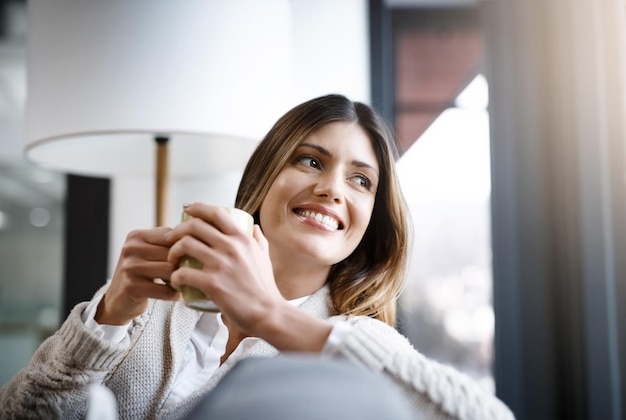 Eén slok koffie is voldoende Bijgesneden opname van een jonge vrouw die geniet van een kopje koffie terwijl ze thuis ontspant