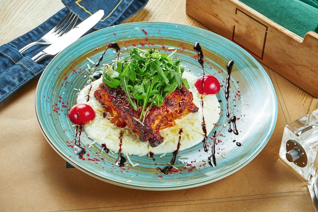 Een smakelijk deel van zelfgemaakte, alleen gebakken lasagne met vlees en kaas, roomsaus en rucola op een keramische plaat op een houten tafel. restaurant tafel instelling