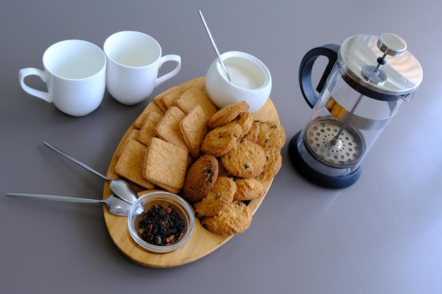 Een smakelijke snack twee kopjes zwarte thee en een bord havermoutkoekjes een houten plank op de grijze achtergrondbladthee