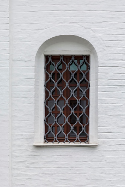 Een smal verticaal raam met tralies in de witte bakstenen muur van het fort Closeup